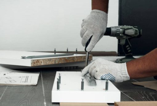 Furniture assembly process. Worker in overalls and white footwear. Using a screwdriver. Do it yourself