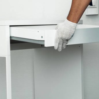 Furniture assembly process. Worker in overalls and white footwear. Installation of a drawer. Do it yourself